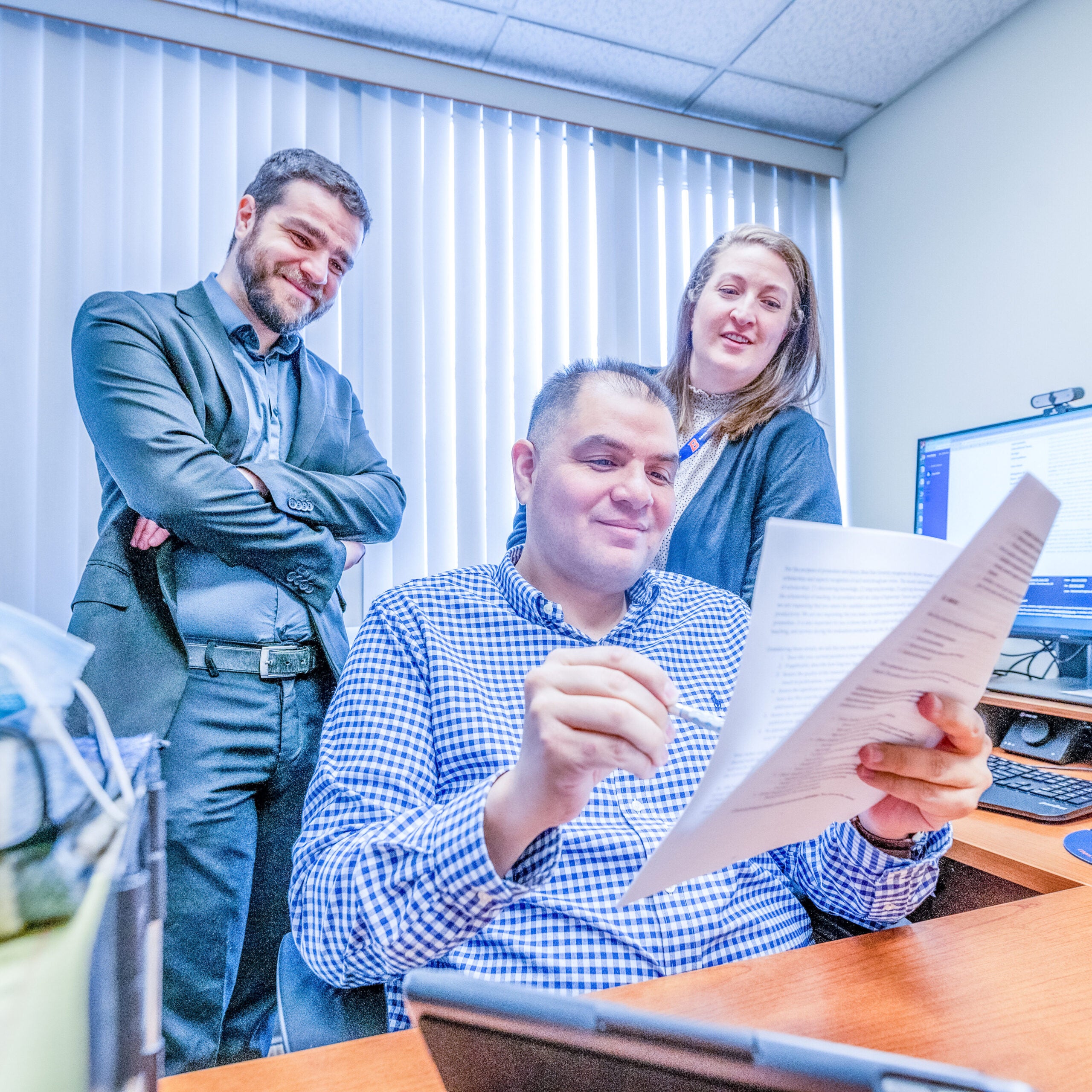Students gather around a faculty member who is discussing a paper