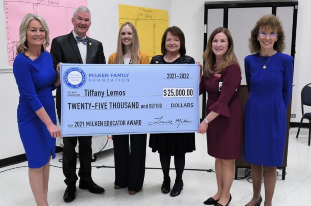Lemos pictured with large check for $25,000 surrounded by administrators
