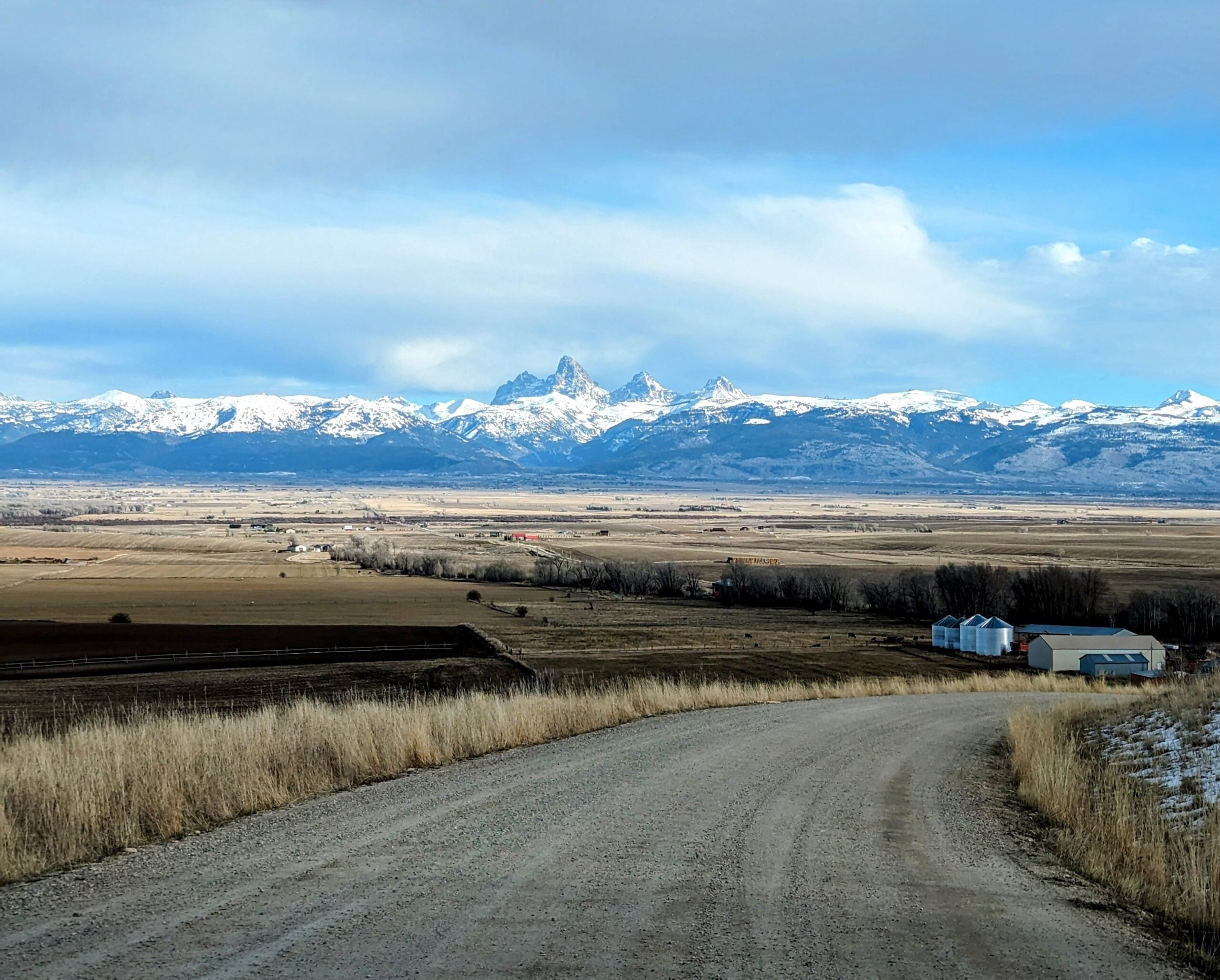 A valley of farmland in the foreground and mountains in the background.